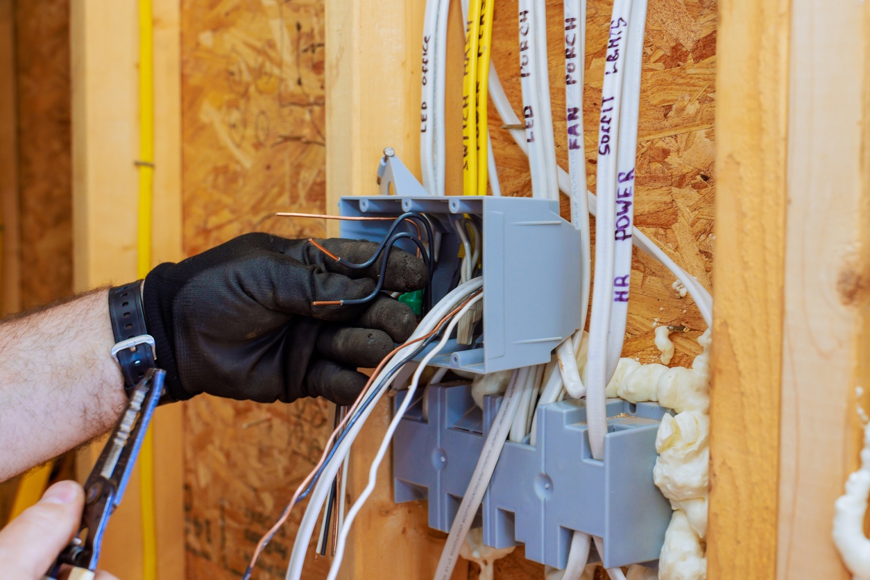 Electrician working on wiring for an outlet box in a building under construction.