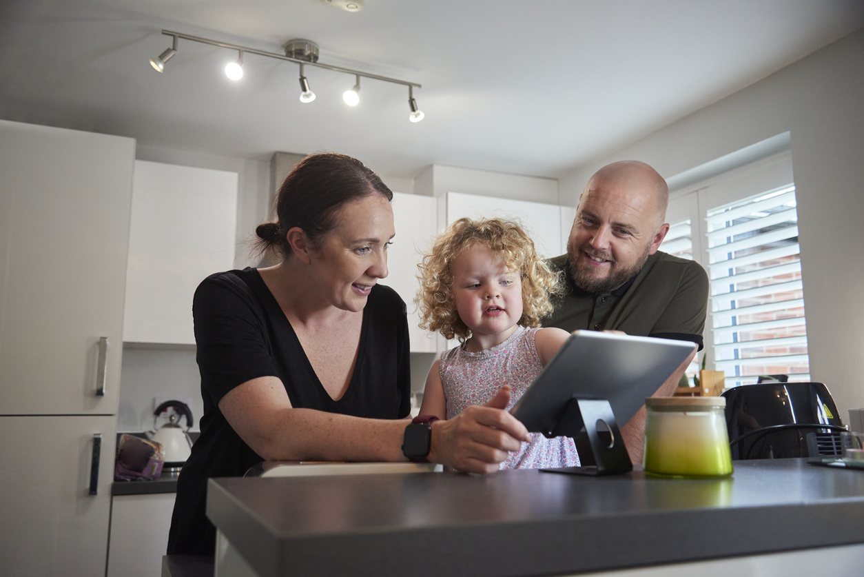A family enjoying time together in a modern kitchen using a tablet.