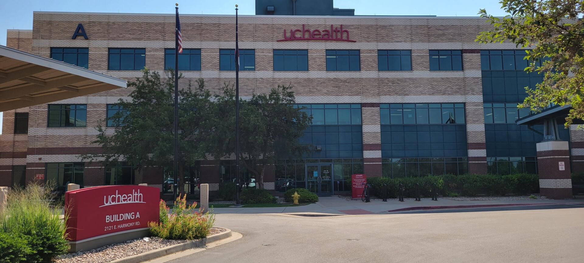 UCHealth Building A with flags and entrance sign, 2121 E. Harmony Rd.