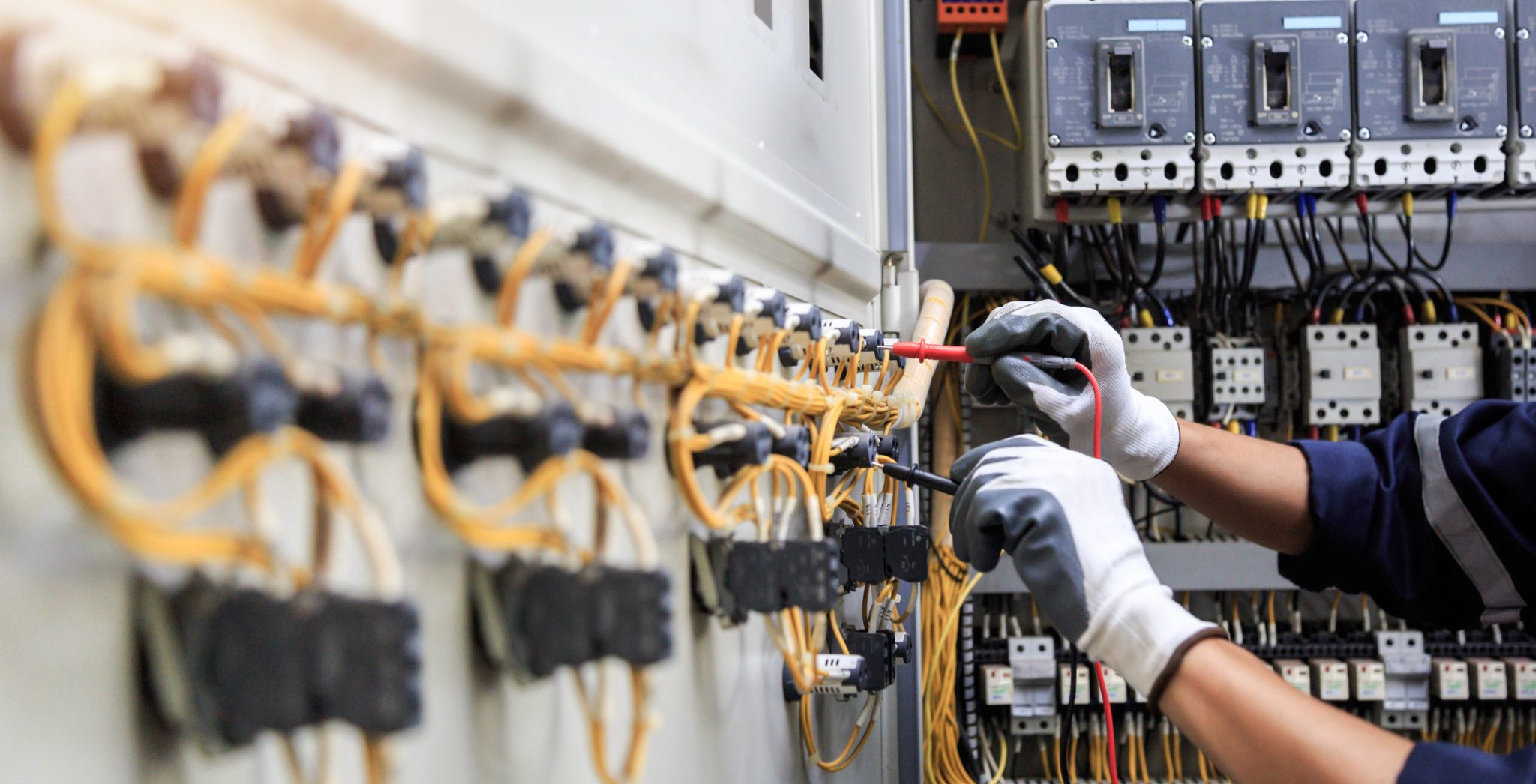 An electrician testing an electrical panel during a commercial electrification services assessment.