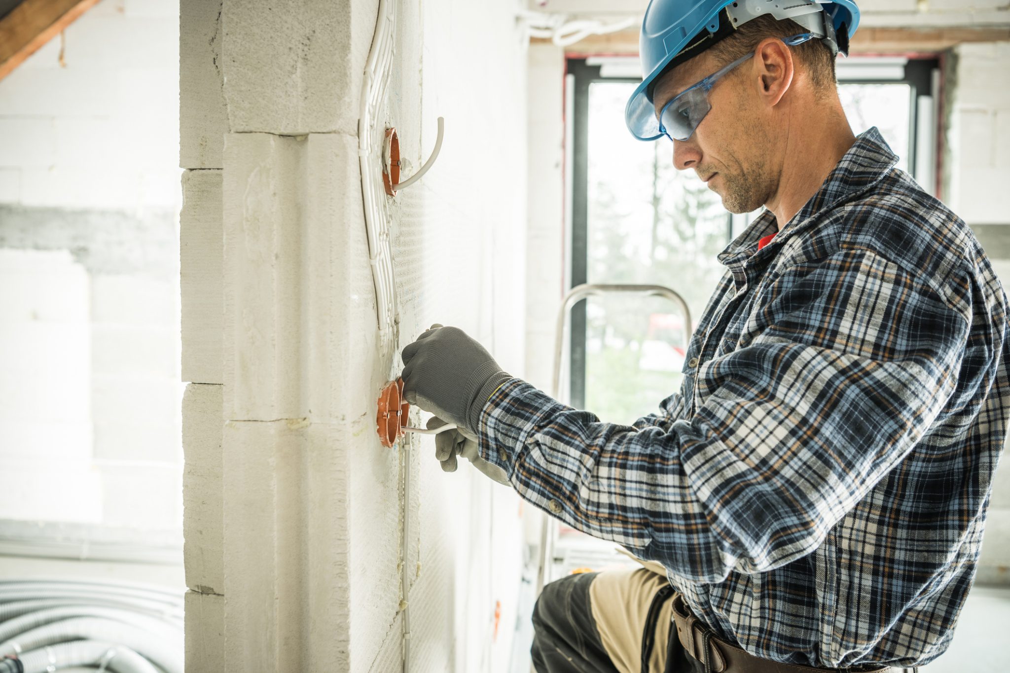 An electrician installs wiring on a commercial construction site during a new development project.