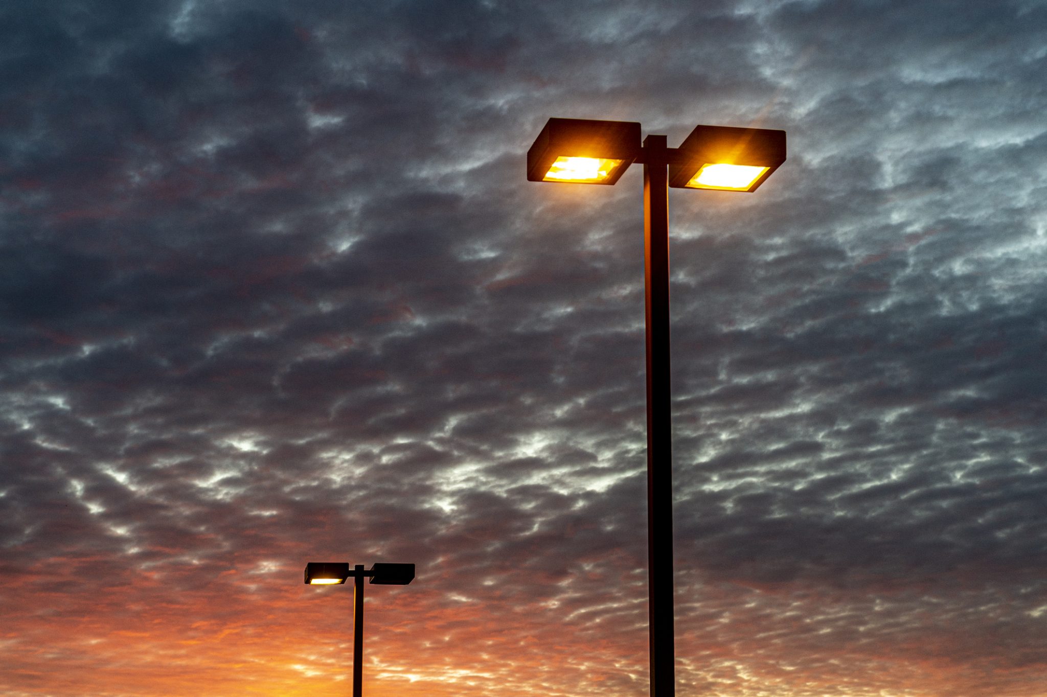 Outdated parking lot lights at dusk awaiting a new parking lot lighting installation.